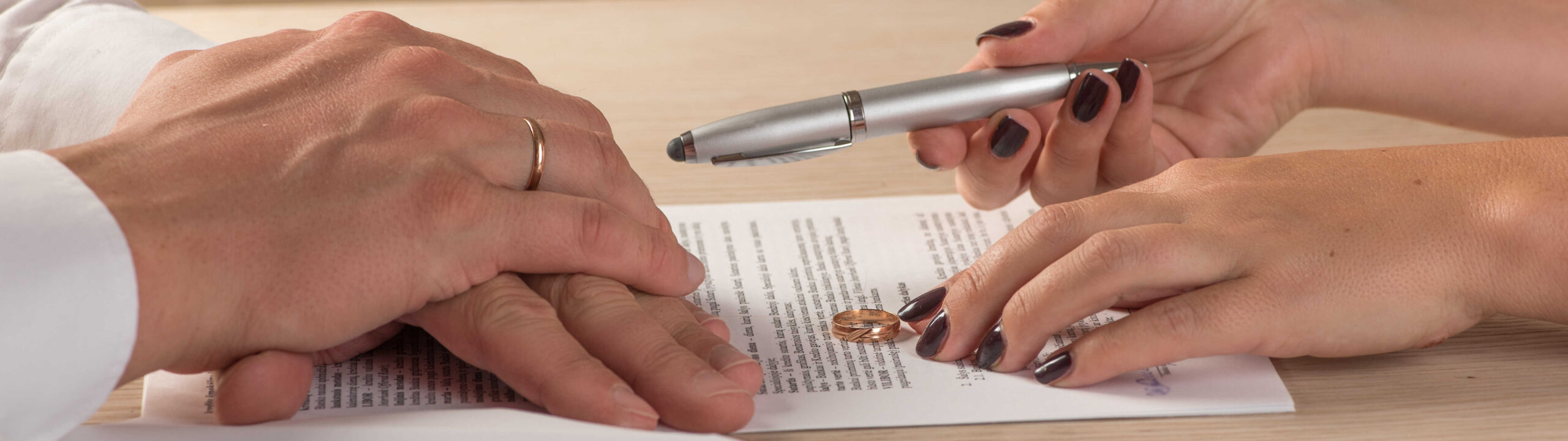 Hands of wife and husband signing divorce documents at their divorce lawyer in London