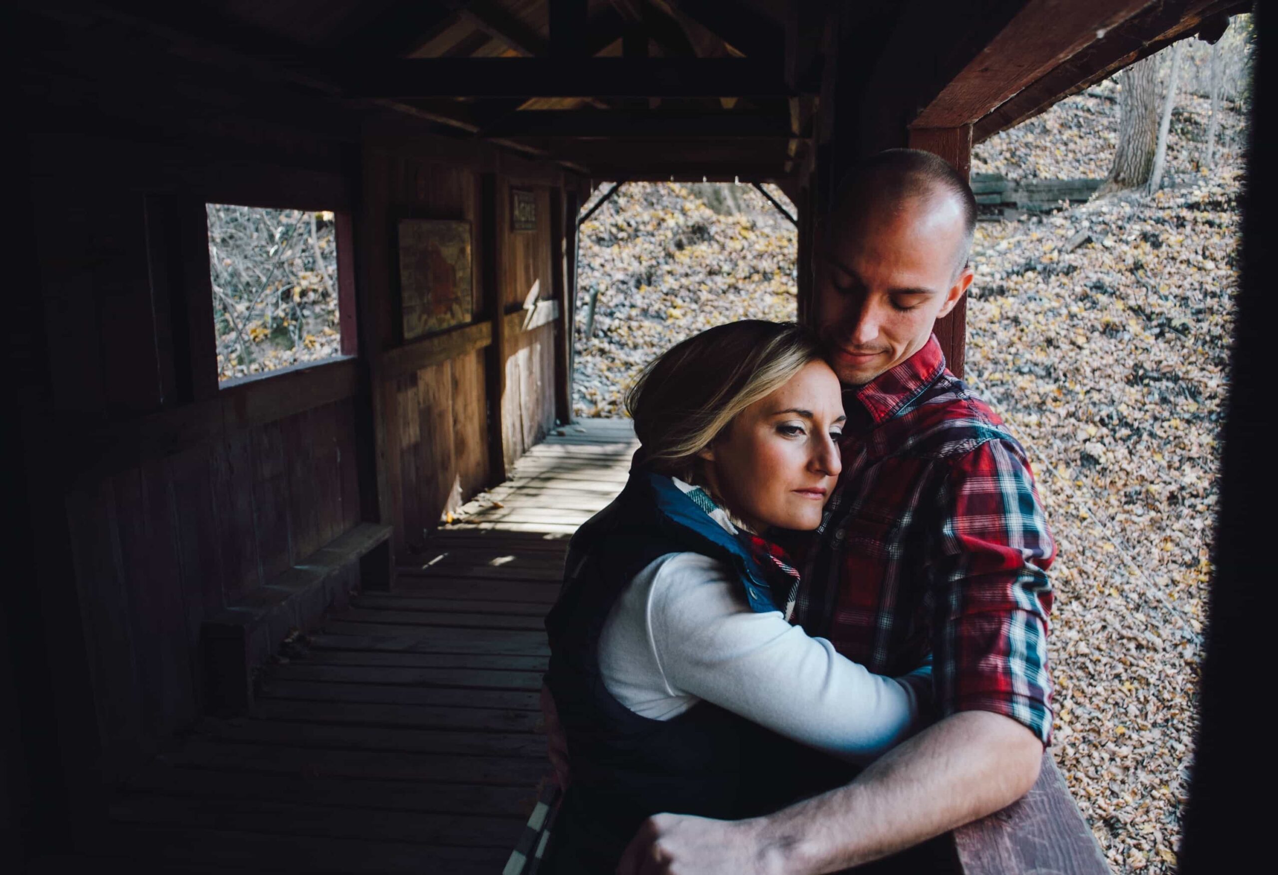 Young couple holding each other on the porch of a wood cabin with country scene in background - vote love divorce solicitor london