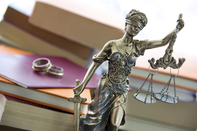 Family and divorce law in England and Wales. Justice statue with sword and scale and marriage certificate