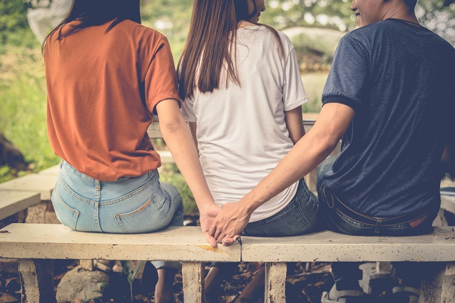Boyfriend and another woman grab hands from behind together without sight of his girlfriend. Divorce concept